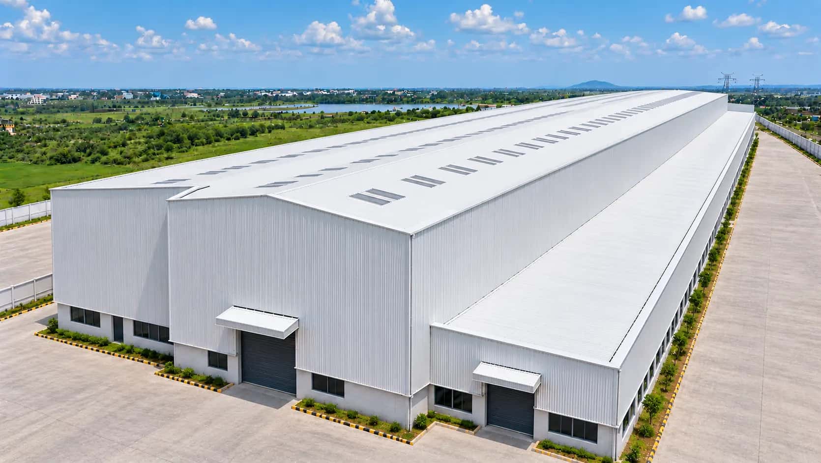 Aerial view of a white factory building with a long roof